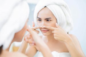 Woman looking in the mirror at her nose