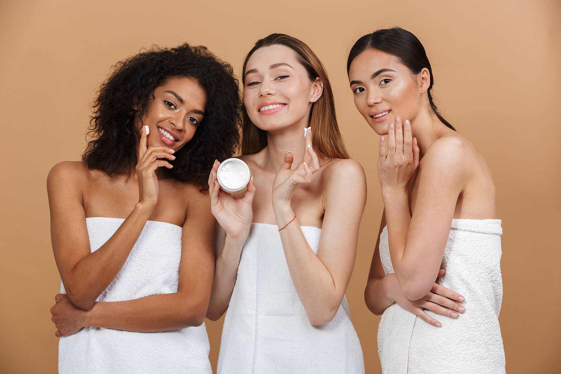 Three women applying face cream