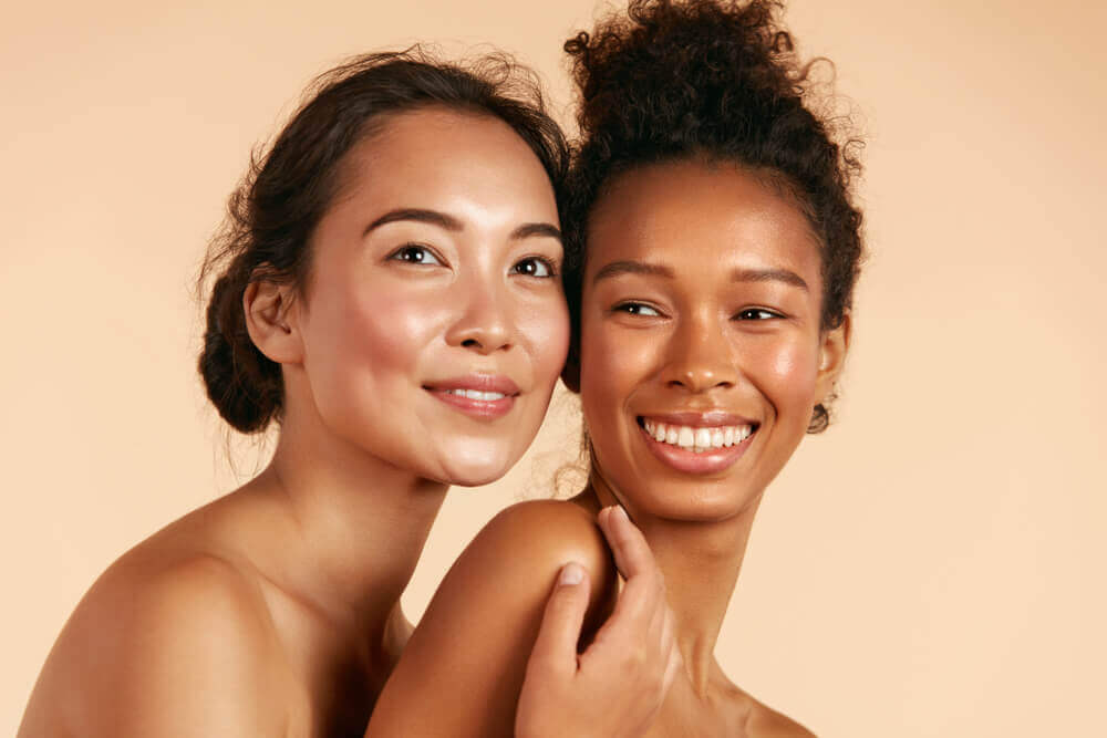 two women smiling with healthy glowing skin