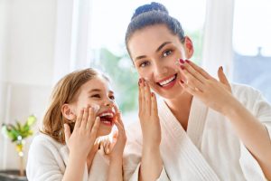 mother and daughter smiling and doing a skincare routine together