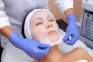 Woman relaxing with sheet mask at medical spa