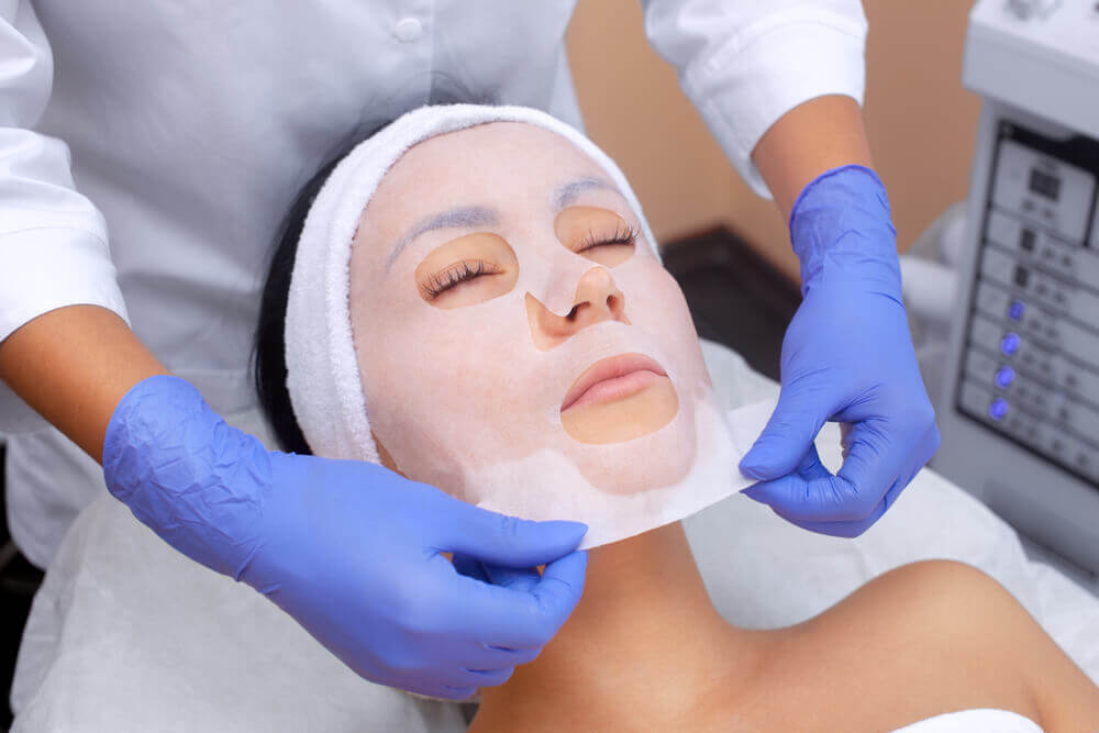 Woman relaxing with sheet mask at medical spa